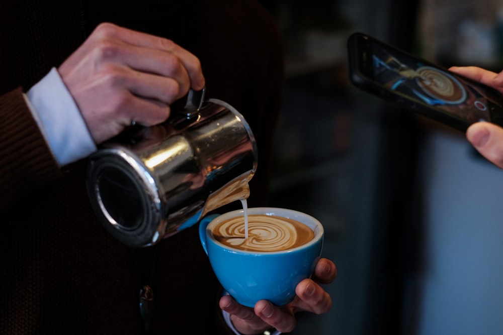 person pouring coffee on blue ceramic mug