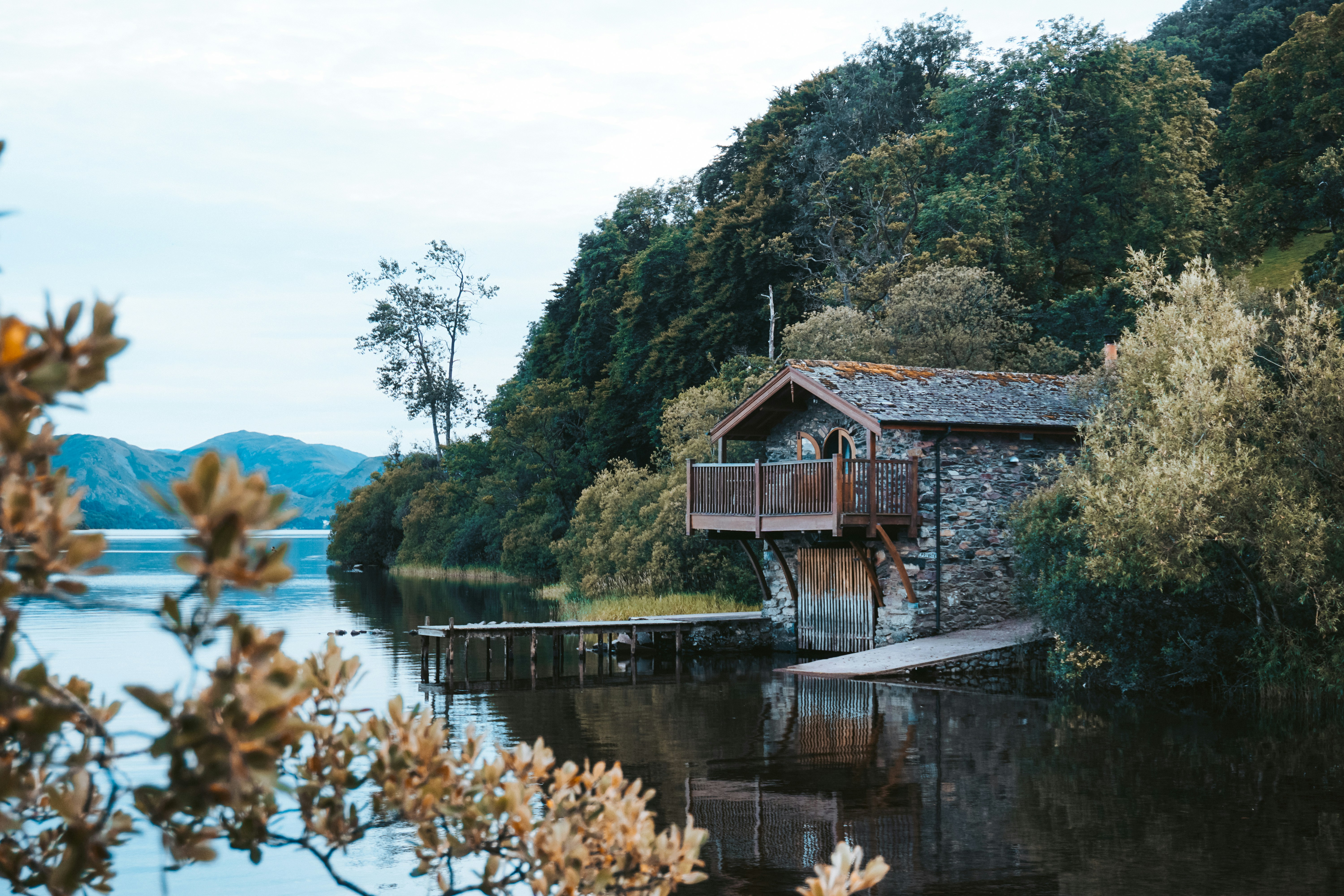 brown wooden house on lake near green trees during daytime