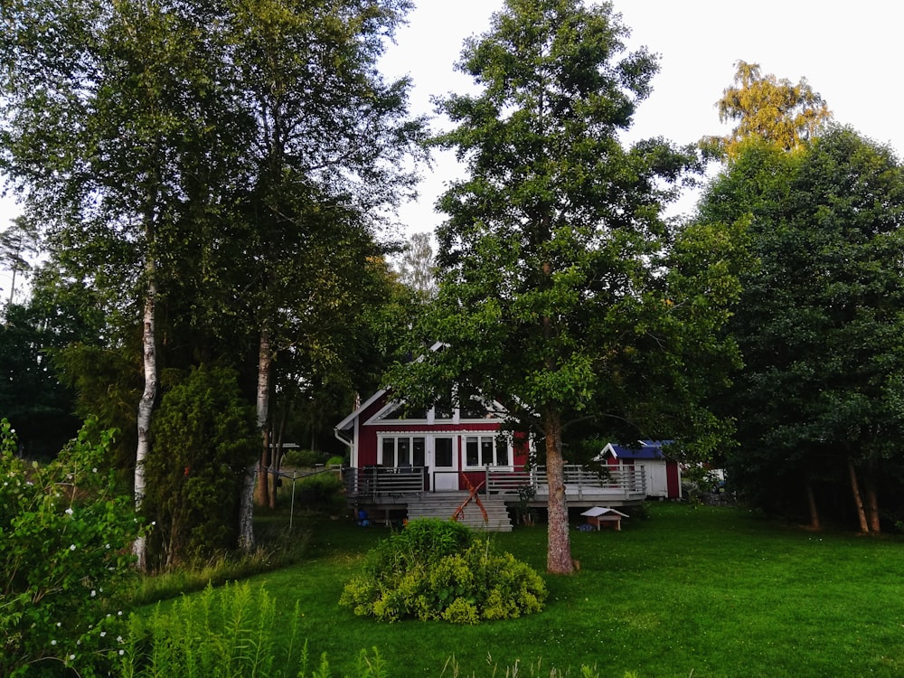 weißes und braunes Holzhaus, tagsüber von grünen Bäumen umgeben
