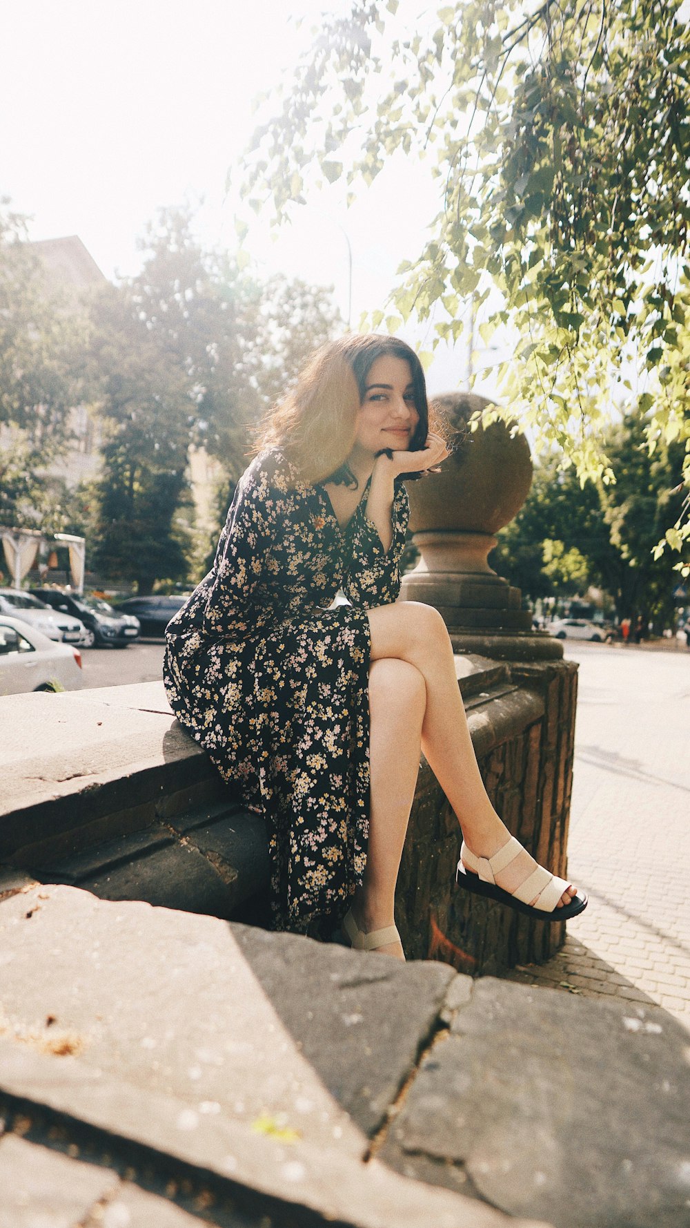 woman in black and white floral dress sitting on brown wooden bench during daytime