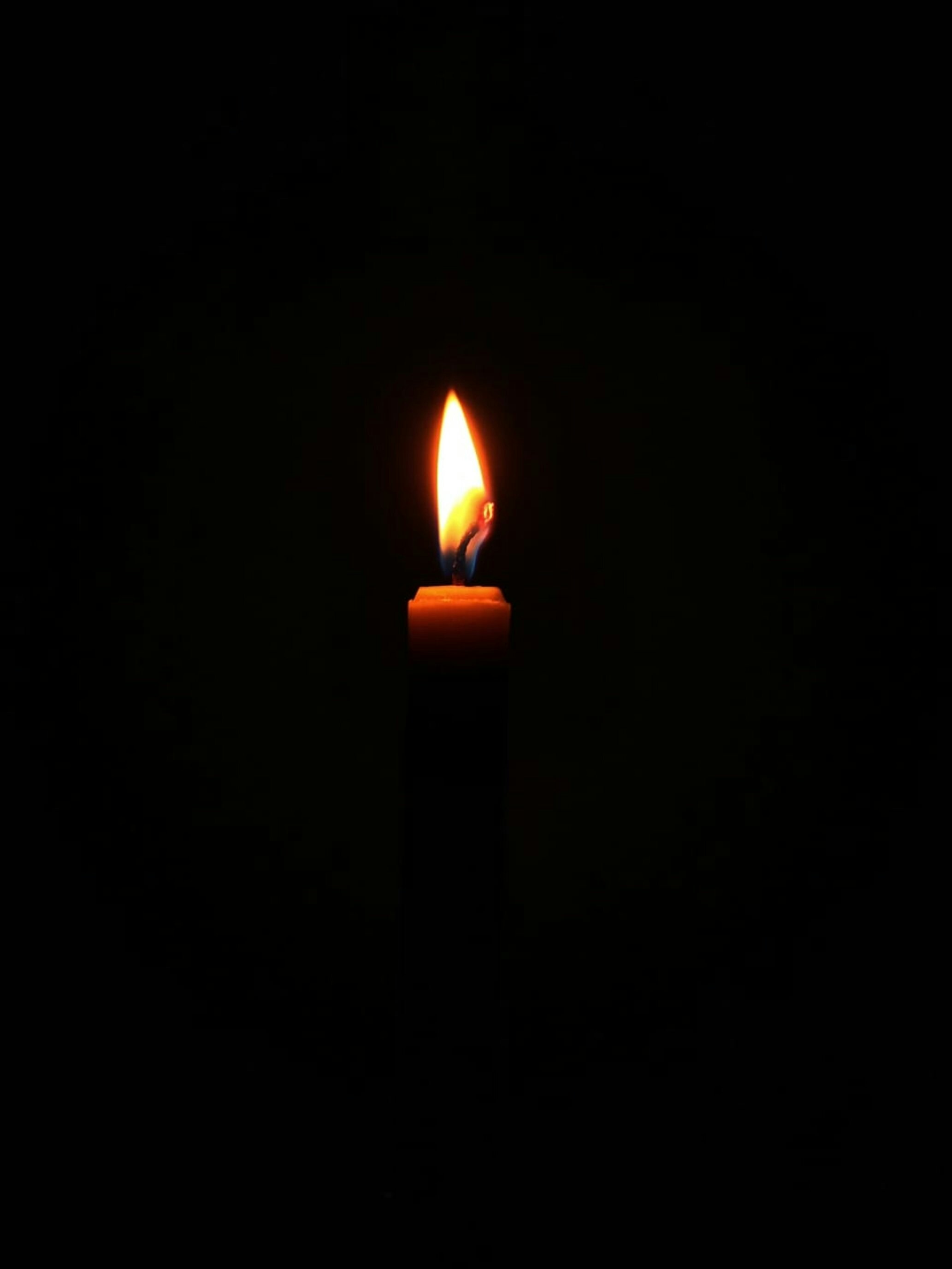 A candle glowing warmly in a dark room representing Jesus as the light.
