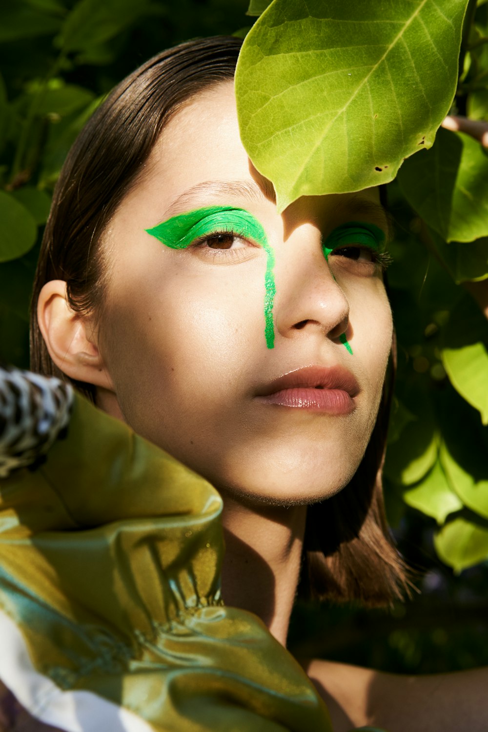 une femme au maquillage vert et à la feuille verte