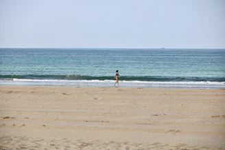 woman in black bikini walking on beach during daytime