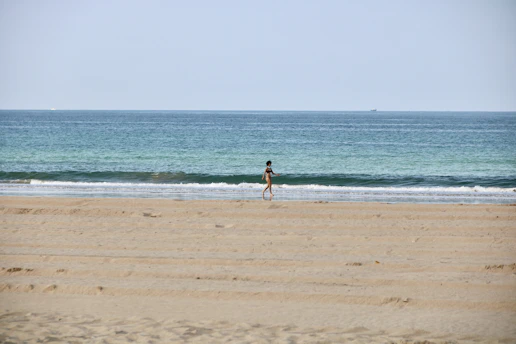 woman in black bikini walking on beach during daytime