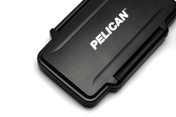 A rectangular black hard case with rounded edges and a textured surface. The case displays the brand name 'PELICAN' in bold white letters across its center.