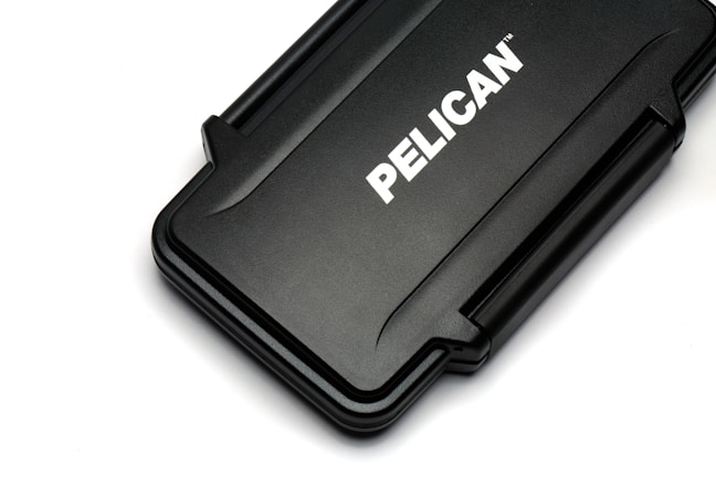A rectangular black hard case with rounded edges and a textured surface. The case displays the brand name 'PELICAN' in bold white letters across its center.