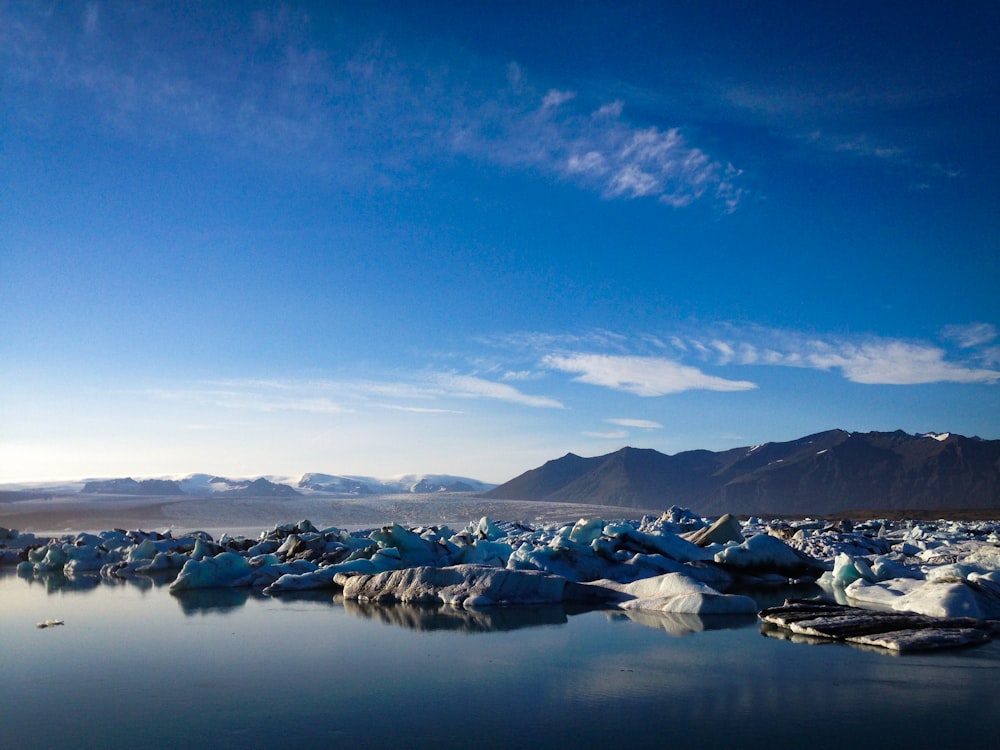 white and black mountains near body of water under blue sky during daytime