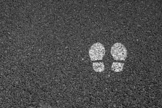 Two white footprints are painted on a dark, textured asphalt surface.
