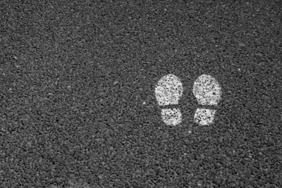 Two white footprints are painted on a dark, textured asphalt surface.