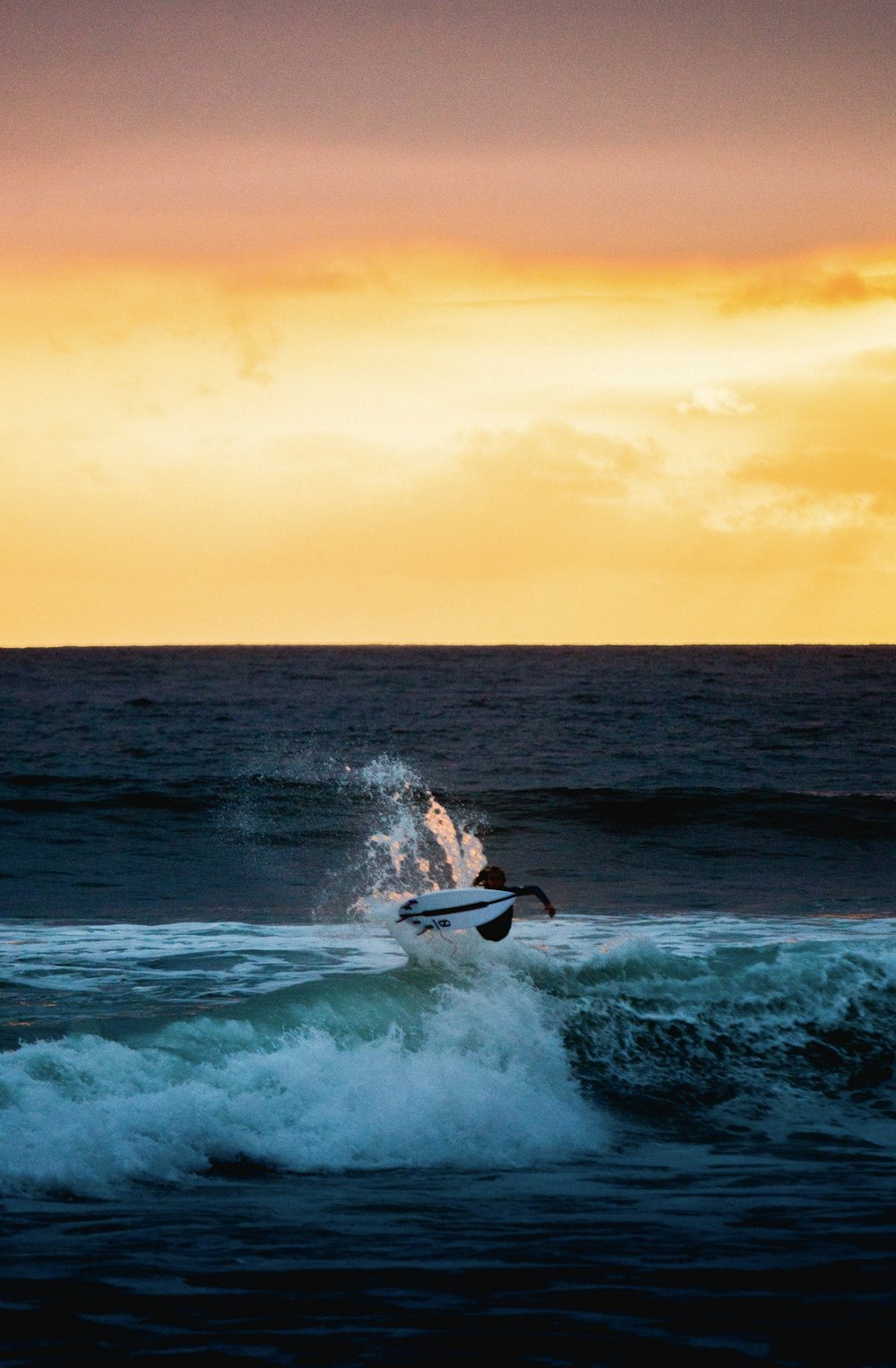 man surfing on sea waves during sunset