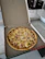 Close-up of a colorful custom-printed pizza box resting on a wooden table next to fresh ingredients.