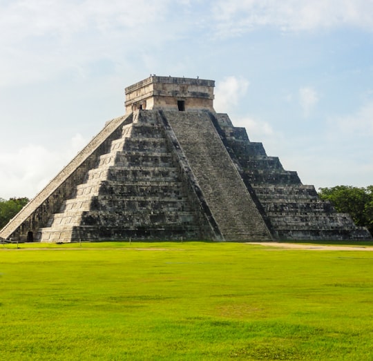 gray concrete building on green grass field during daytime in Yucatan Mexico