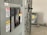 A close-up view of an industrial electrical panel with various switches and warning labels. The panel features caution and danger signs in multiple languages, and its metallic surface is complemented by the soft lighting of the room.