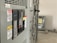 A close-up view of an industrial electrical panel with various switches and warning labels. The panel features caution and danger signs in multiple languages, and its metallic surface is complemented by the soft lighting of the room.