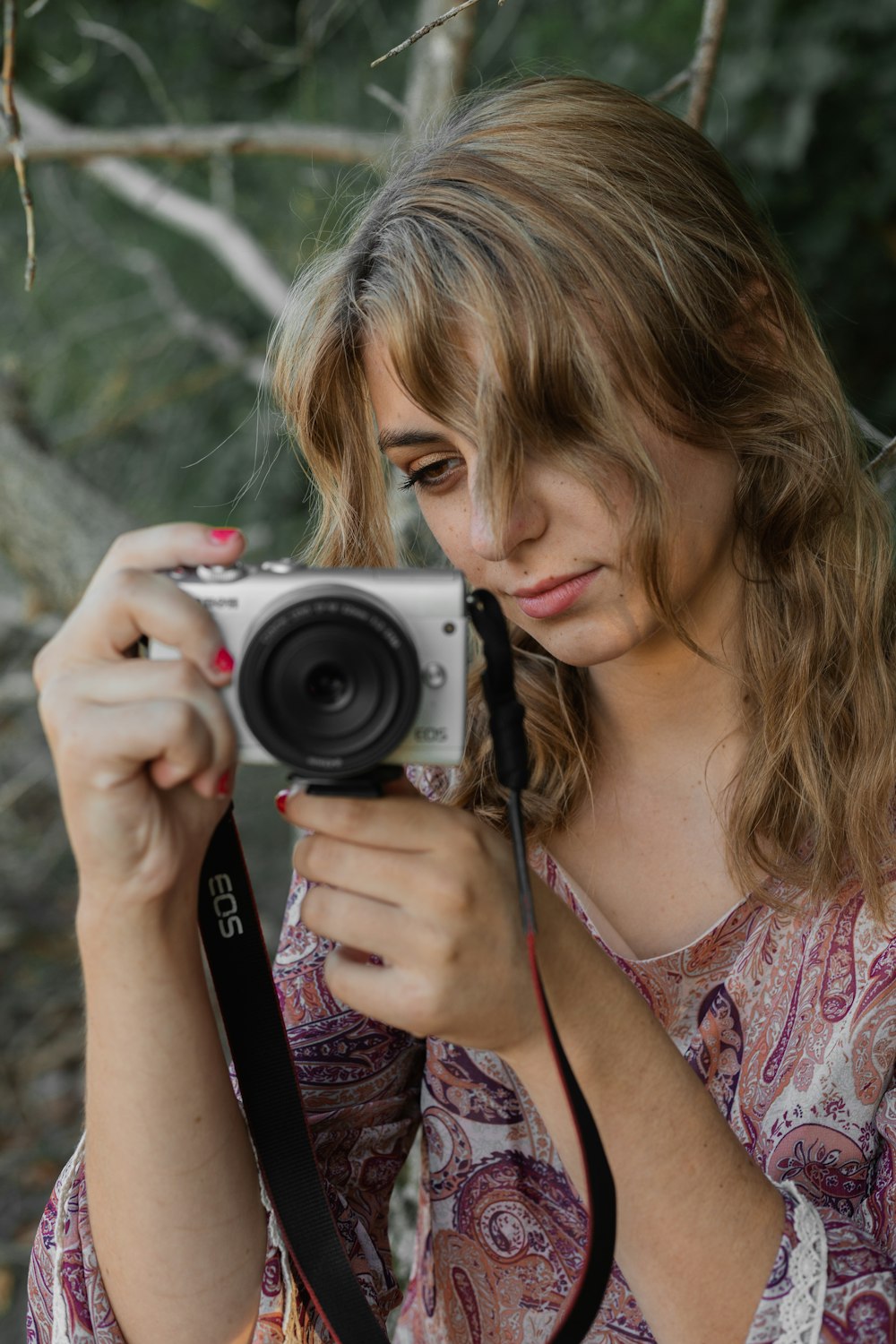 woman in pink and white floral shirt holding black and silver camera