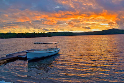 Sunset view over a serene lake with a small boat docked nearby.