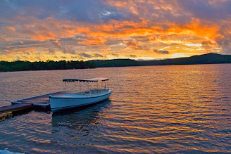 Sunset view over a serene lake with a small boat docked nearby.