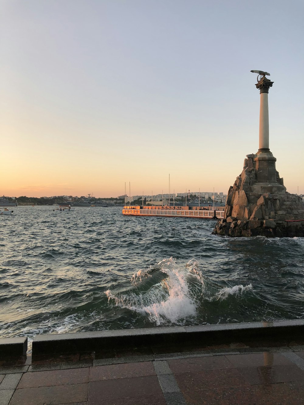 white and brown lighthouse on brown rock formation near body of water during daytime