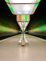 Wide shot of a futuristic subway platform featuring minimalist design elements and glowing green accents, emphasizing negative space and user-centered layout.