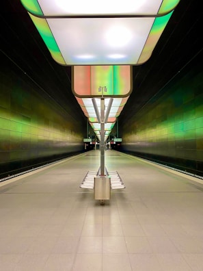 Wide shot of a futuristic subway platform featuring minimalist design elements and glowing green accents, emphasizing negative space and user-centered layout.