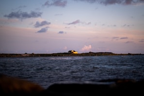 A tranquil coastal landscape at sunset with soft clouds.