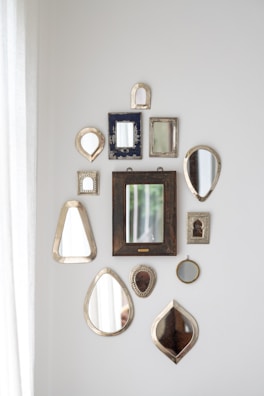 Collection of handcrafted mirrors and wooden decor arranged on a neutral background.