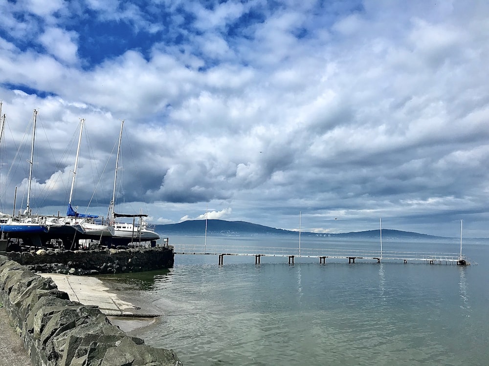 white and black boat on sea under blue sky and white clouds during daytime