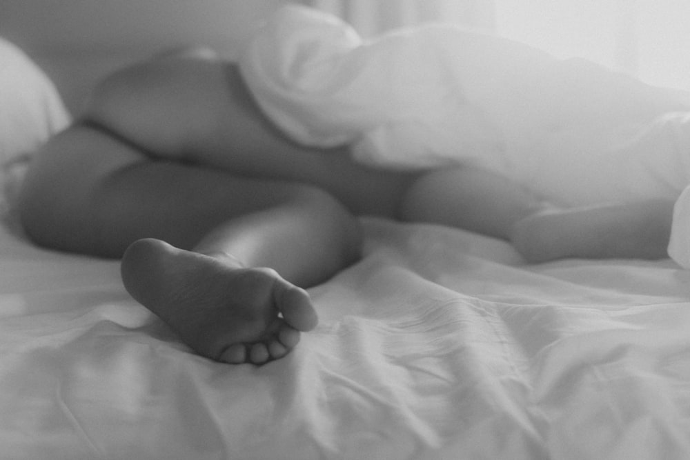foto in scala di grigi di bambino sdraiato sul letto