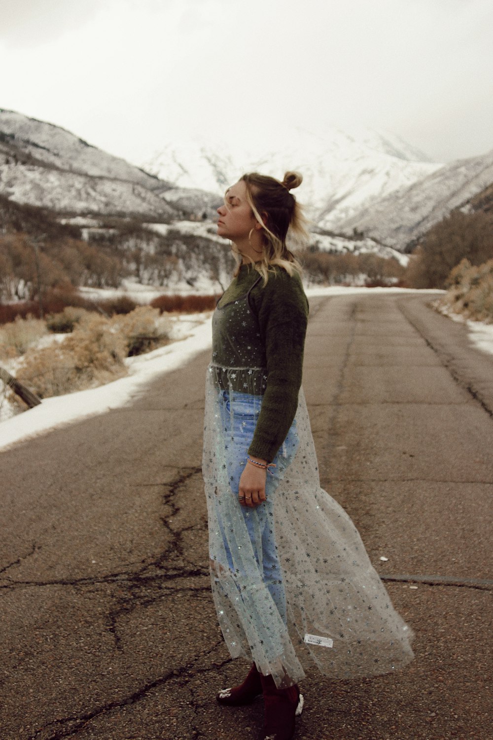 woman in black jacket and blue denim jeans standing on road during daytime