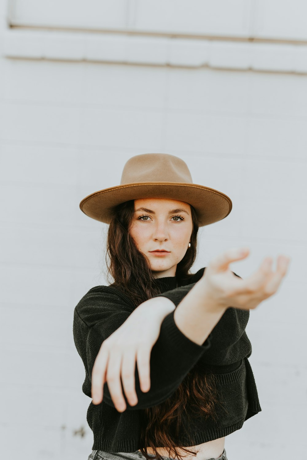 Mujer con camisa negra de manga larga con sombrero marrón
