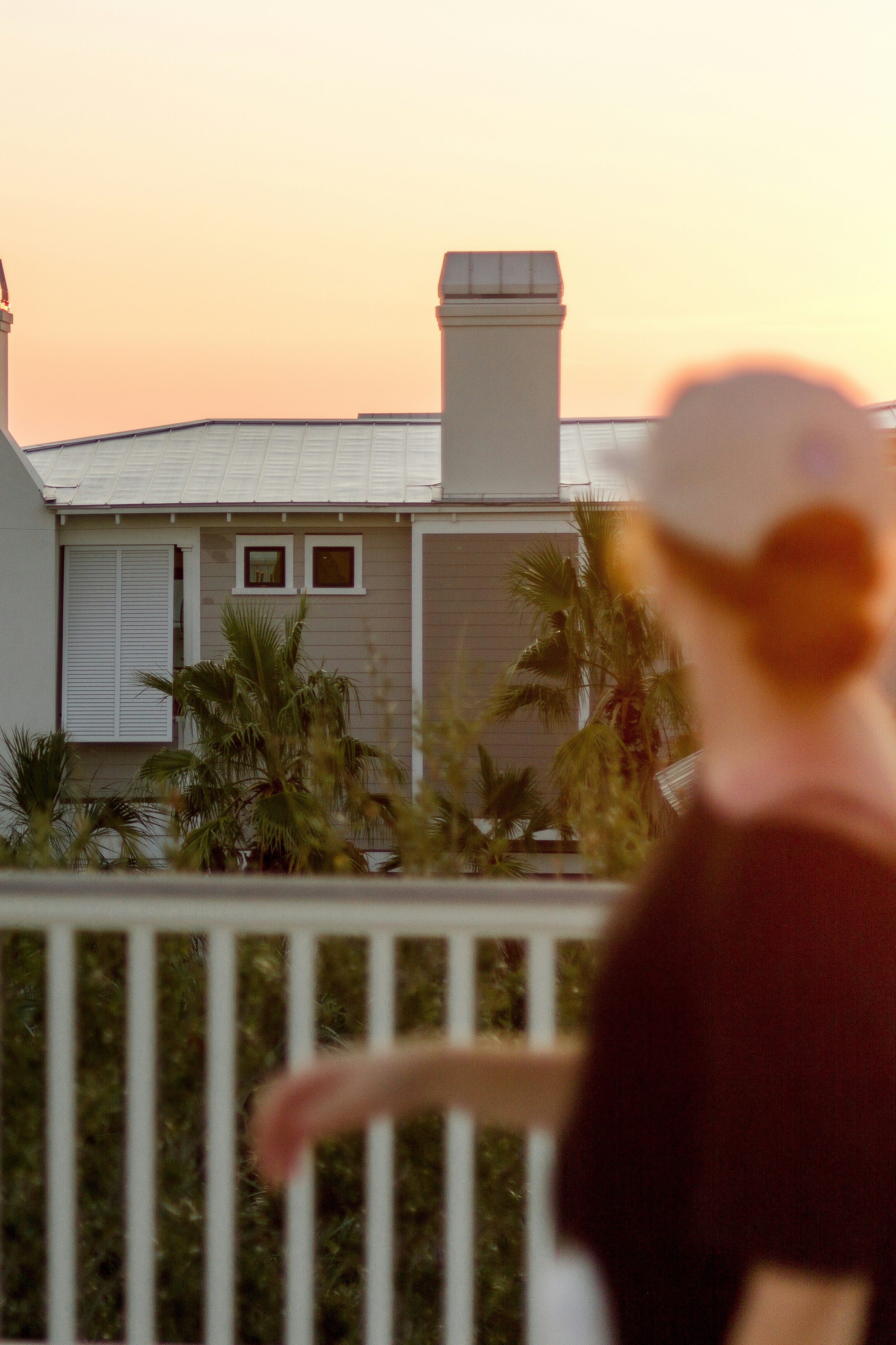 Persona in camicia nera a maniche lunghe in piedi vicino alla staccionata di legno bianca durante il giorno