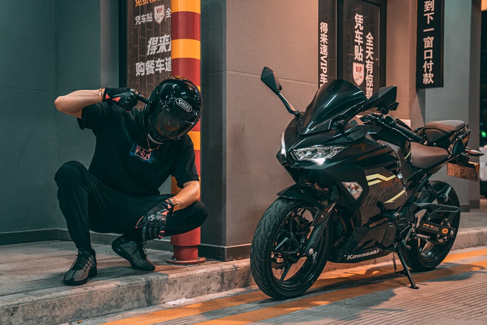 Homme en veste noire et casque noir sur une moto de sport noire