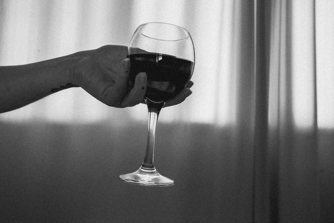 grayscale photo of person holding wine glass