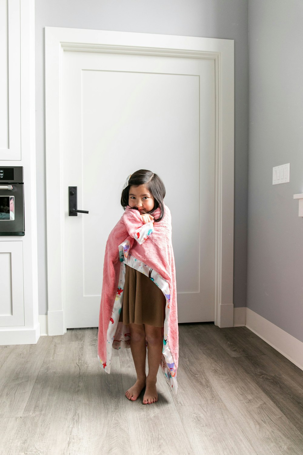 girl in pink long sleeve shirt standing beside white wooden door