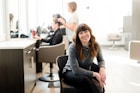 woman in gray long sleeve shirt and black pants sitting on black chair