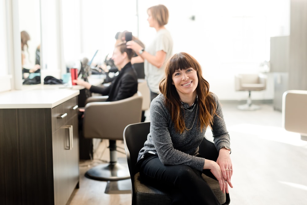 woman in gray long sleeve shirt and black pants sitting on black chair