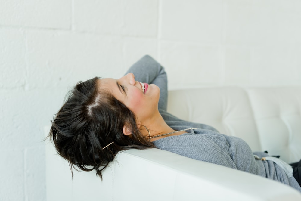 woman in gray long sleeve shirt lying on bed