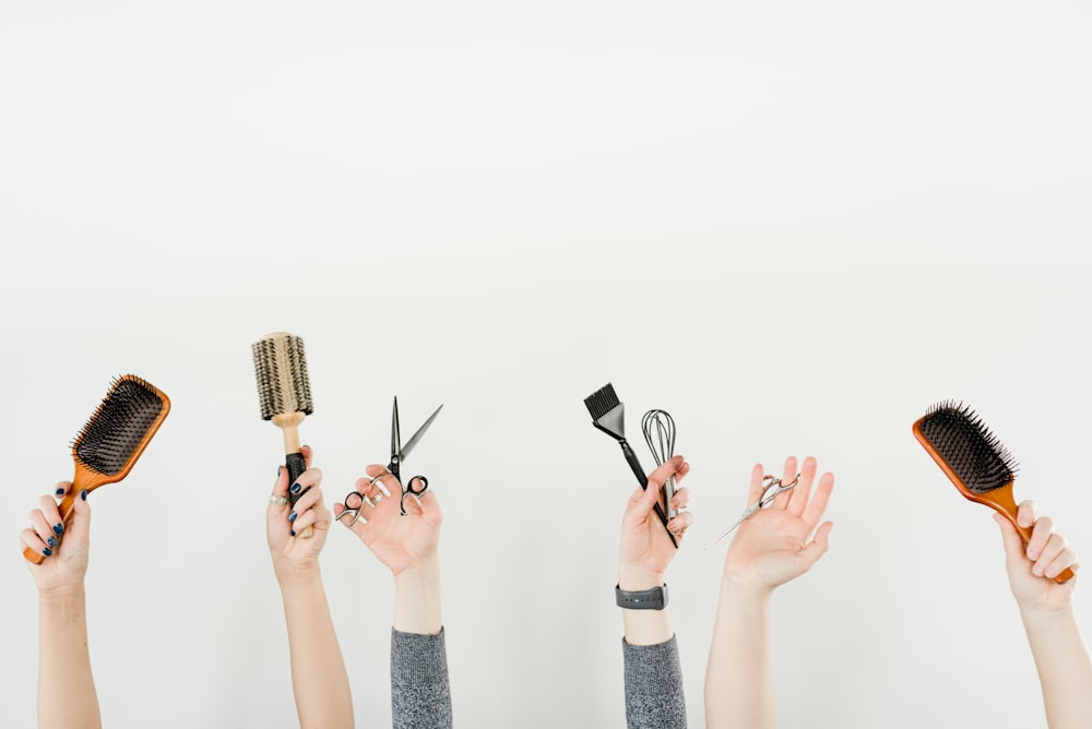 person holding silver and black hair brush