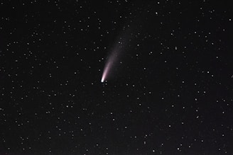 A bright comet with a faint tail is visible against a dark, starry sky. The stars are scattered evenly across the background.