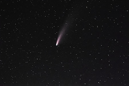 A bright comet with a faint tail is visible against a dark, starry sky. The stars are scattered evenly across the background.