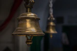 Close-up of a brass bell being rung during a puja ceremony.