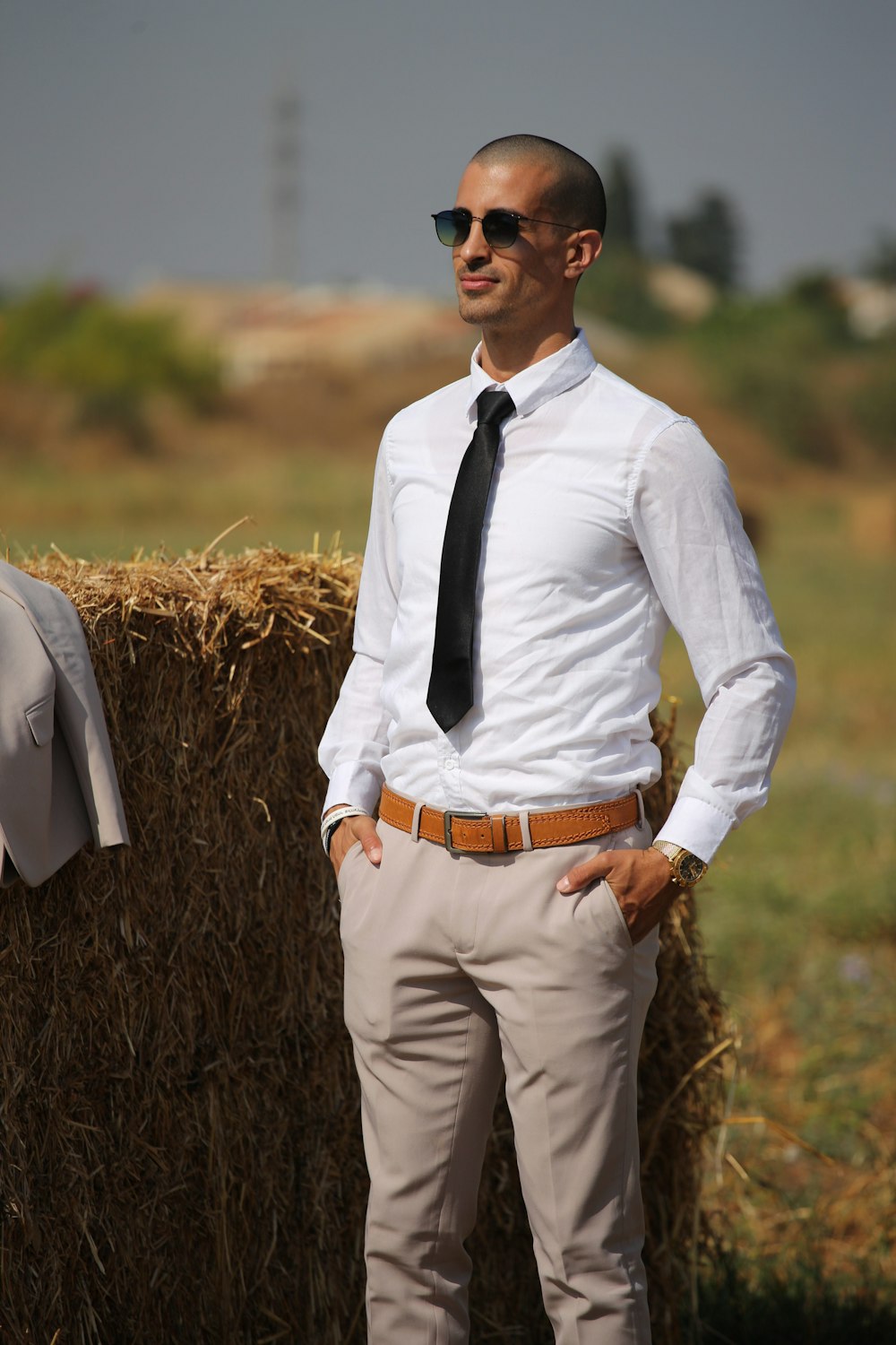 man in white dress shirt and brown pants standing on brown grass field during daytime