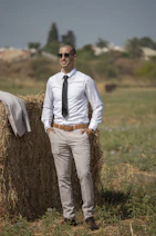 man in white dress shirt and brown pants standing on brown grass field during daytime