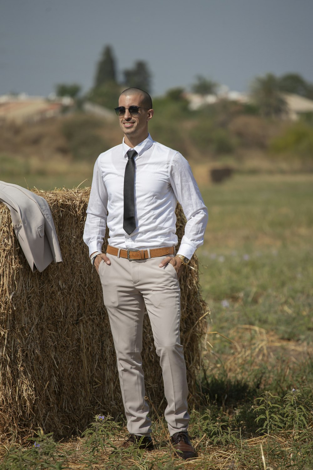 man in white dress shirt and brown pants standing on brown grass field during daytime