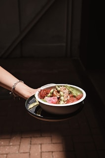 person holding white ceramic bowl with food