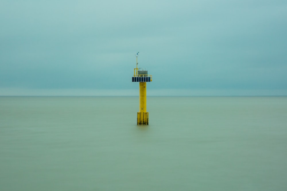 yellow and white tower on the middle of the sea