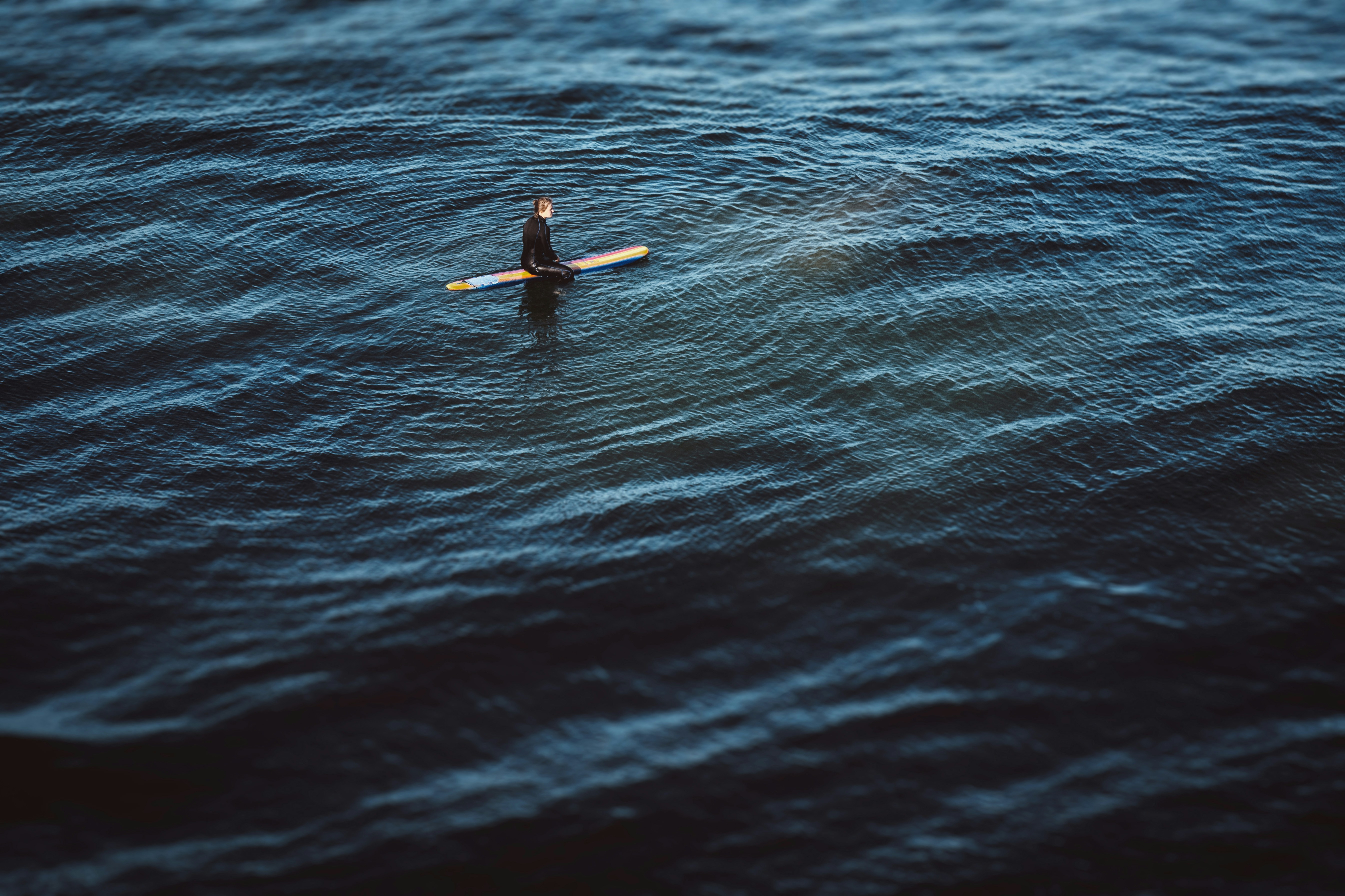 man in black wet suit riding on yellow surfboard in the middle of the sea during, Waiting