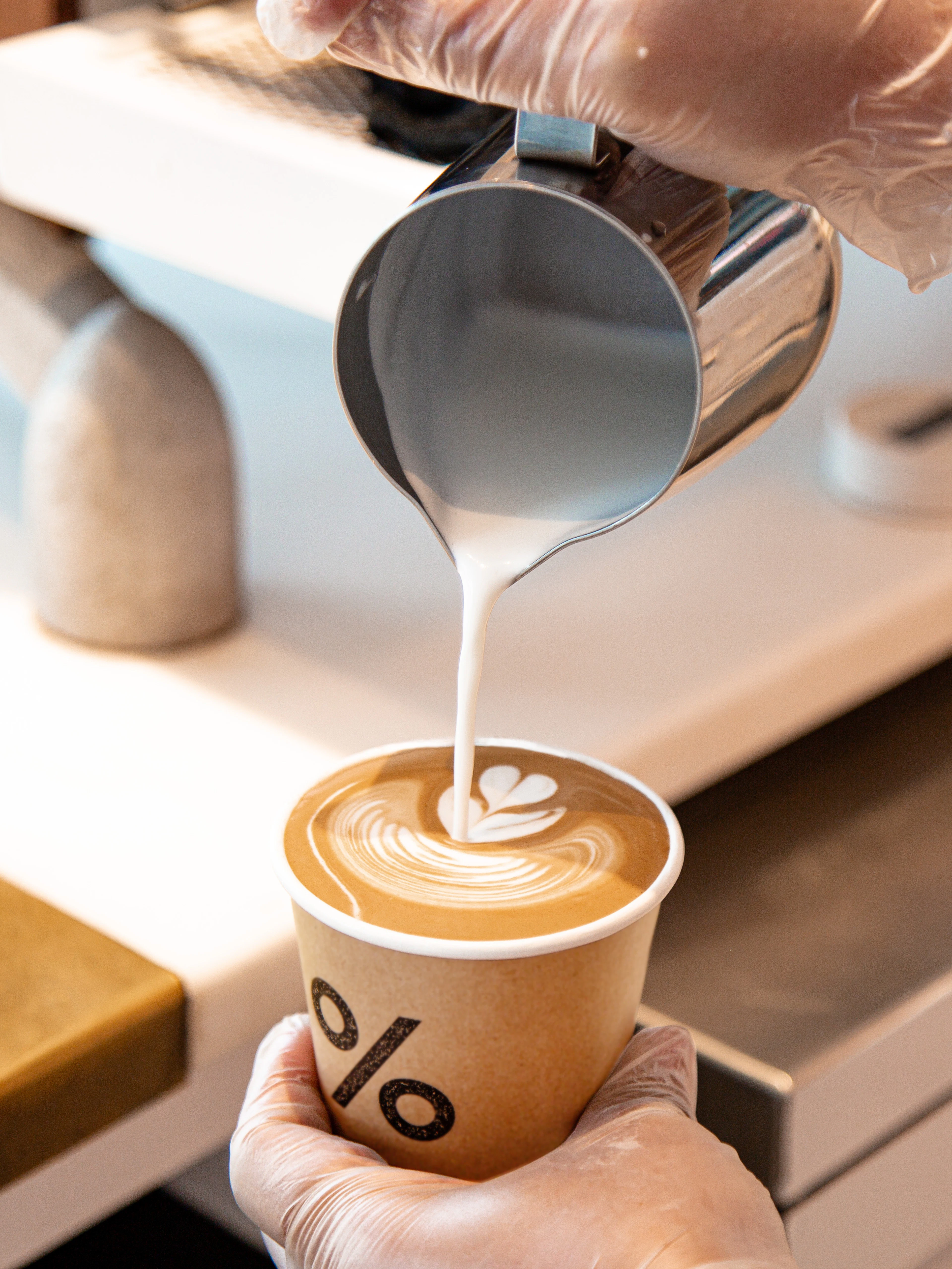 Latte art being poured into a takeaway cup