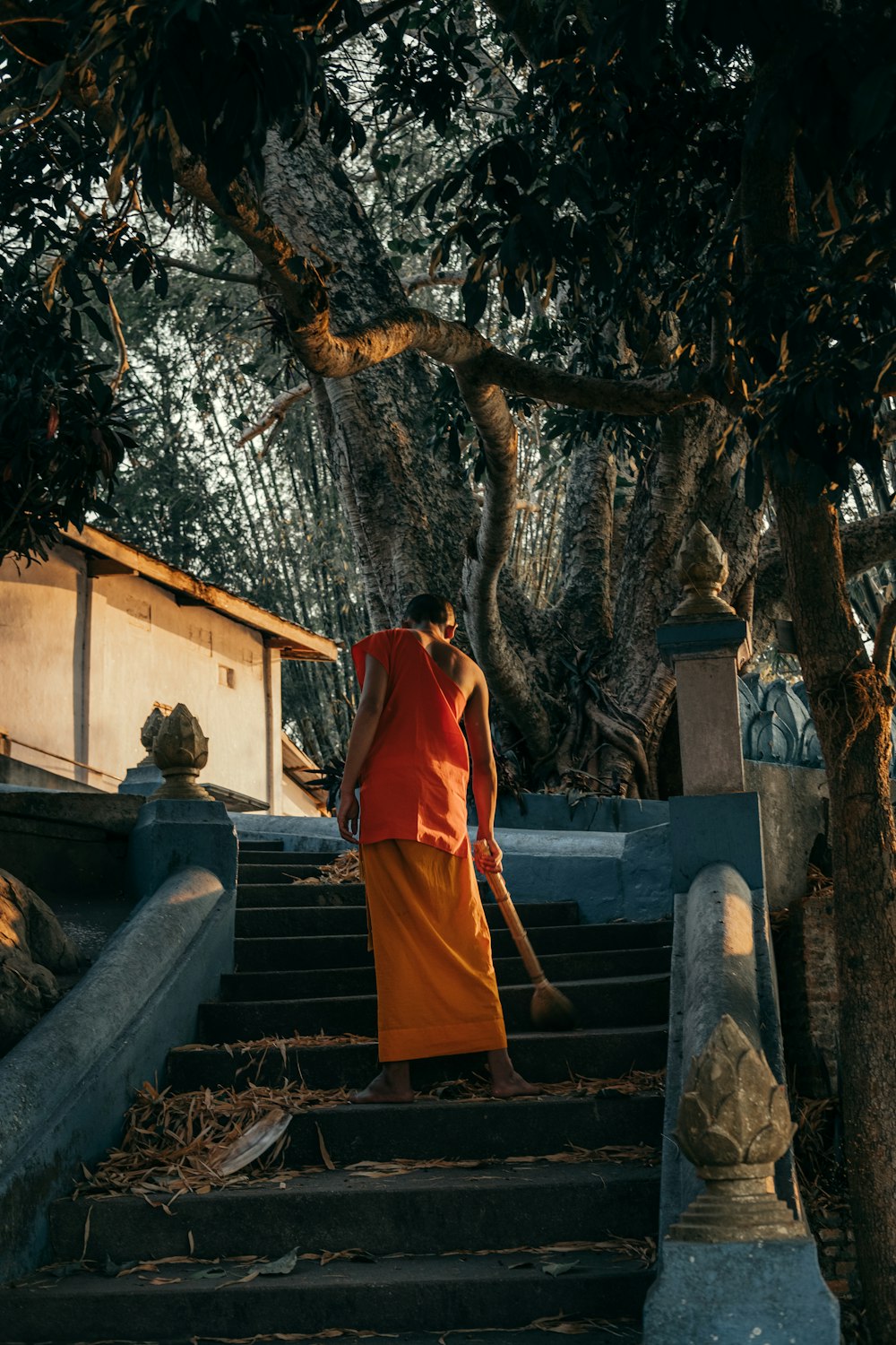 woman in orange robe standing on gray concrete stairs