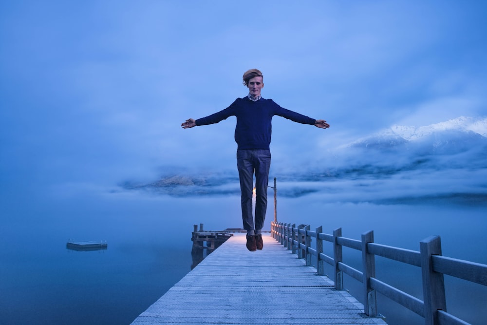 man in black long sleeve shirt standing on wooden dock during daytime